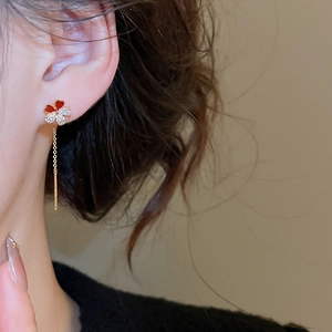 Detail view of flower drop earrings with gold plating, zircons, and red enamel on model