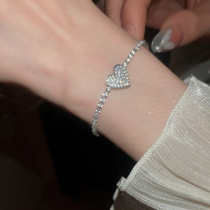 Detailed view of sparkly zircon heart pendant on elegant silver tennis bracelet