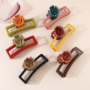 Dettaglio di grandi mollette per capelli a rosa in sei colori vintage su fondo beige