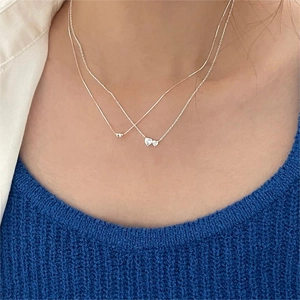 Close-up of double layered silver heart necklaces with sparkling cubic zirconia on neck
