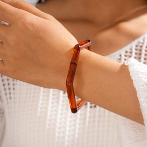 Details des bernsteinfarbenen geometrischen Acryl-Armreifs mit Vintage-Struktur