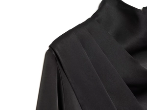 Gros plan détaillé des plis sur l'épaule de ce chemisier élégant en satin noir fin
