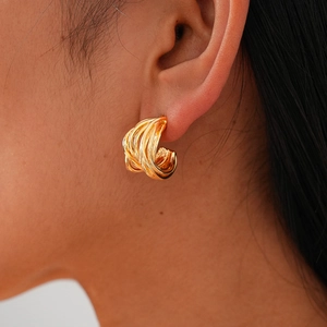 Minimalist gold-plated geometric twisted C-shape earrings worn by a model in profile