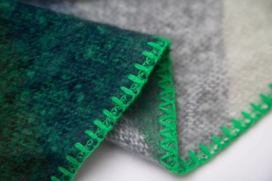 Macro shot of thick gradient felt fabric with bright green overcast stitching details