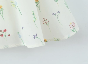 Nahaufnahme des floralen Stoffes mit roten Blumen und feinen Details am Saumabschluss