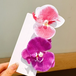 Detailed view of pink and purple orchid hair clips with elegant pearl center accents