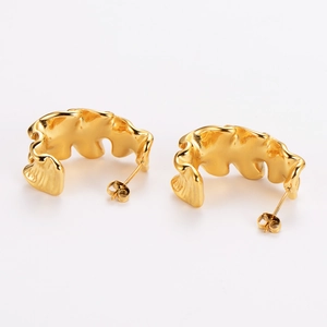 Macro shot of 18k gold plated wave earrings featuring a polished mirror surface finish