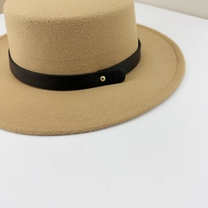 Macro detail of camel wool felt hat showing black leather strap and golden metal buckle