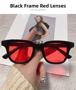 Close-up of square black frame sunglasses with red lenses and metal rivet details
