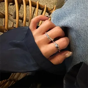 Detail view of minimalist silver rings including twisted band and ball bead on female hand