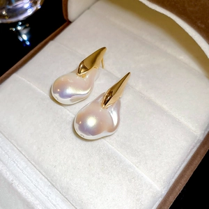 Macro di orecchini di perle barocche placcati in oro 18K su portagioie in velluto beige