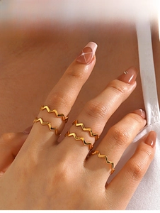 Close-up of a hand wearing five minimalist 18K gold-plated wavy stackable rings
