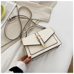Detail view of cream white PU leather crossbody bag with golden hardware and black trim edges