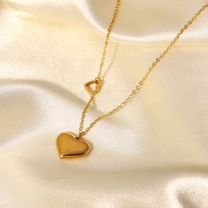 Detail of 18K gold-plated double heart pendant necklace on elegant cream satin fabric