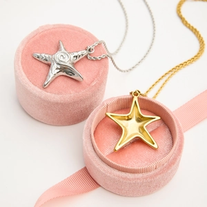 Detailed shot of gold and silver star pendants in pink velvet jewelry boxes