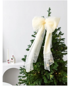 Close-up of a creamy white organza ribbon bow on a Christmas tree with warm lights