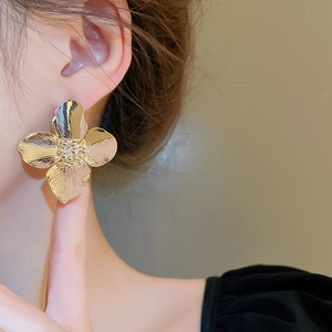 Golden metal flower earrings with sparkling zircon center worn by model for elegant style