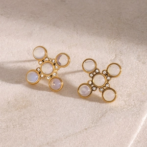 Macro shot of gold cross star earrings with opal gemstones and sparkling rhinestones
