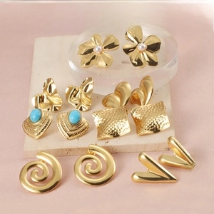 Detail of assorted gold geometric earrings including pearls and blue stones on stone display