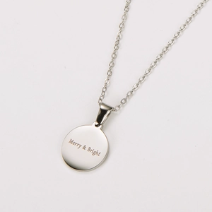 Close-up of silver round pendant with Merry & Bright gold engraving on metal chain