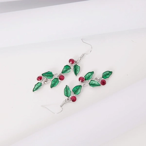 Detail of Christmas earrings featuring green enamel leaves and red berry rhinestone studs