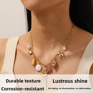 Gros plan d'un collier en acier doré avec perles et pendentifs tulipes porté par un mannequin