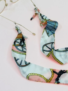 Detailed macro view of silk scarf eyewear chain with carriage print and gold metal clasp