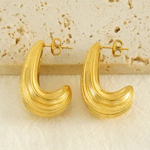 Gold-plated stainless steel curved earrings with vertical stripes on travertine stone