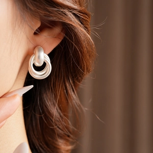 Close-up of matte silver geometric double hoop earrings worn by a female model