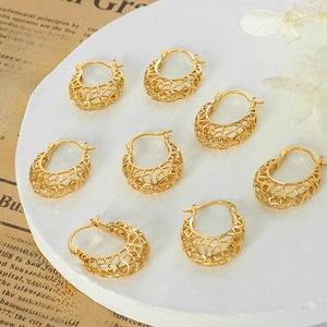 Baroque hollow U-shaped gold earrings set on a vintage plate with artistic dry flowers