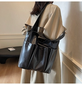 Brown vintage faux leather tote bag with large front pockets shown on model shoulder
