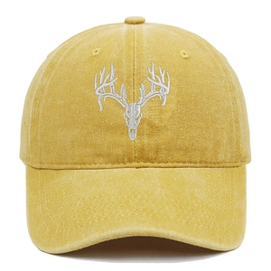 Detailed embroidery of a white deer skull on a vintage yellow washed cotton baseball cap