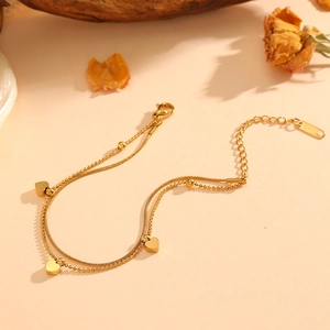 Double-layered 18K gold snake chain bracelet with heart pendants and metal beads
