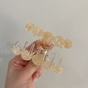 Detail of transparent beige gradient hair claw clip with rounded teeth held by hand