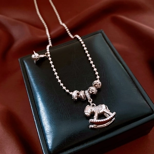 Détail d'un pendentif cheval à bascule en or rose avec zircons sur une boîte à bijoux noire