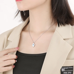 Close-up of Hamsa Evil Eye pendant necklace worn by model against a white background
