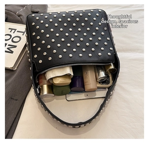 Detailed internal view of black rivet shoulder bag showing spacious storage capacity