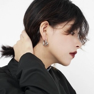 Close-up of a silver heart-shaped earring worn on a model against a white background