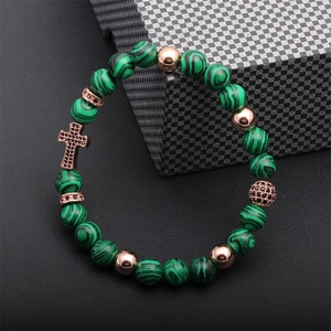 Detail of cross charm beaded bracelet with green malachite stones and rose gold accents
