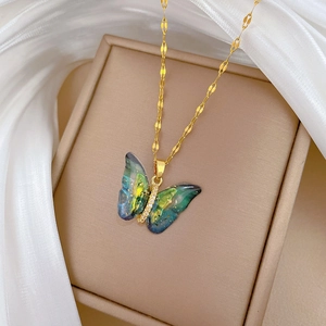 Detail of blue and green butterfly pendant with rhinestones on a gold chain