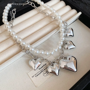 Detail of double-layer necklace with white pearls and silver heart pendants in jewelry box