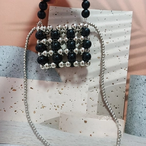 Close-up of handmade beaded mini bag with silver and black metallic beads and strap