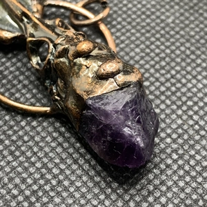Vue macro d'un pendentif tête de corbeau en bronze vintage avec cristal violet