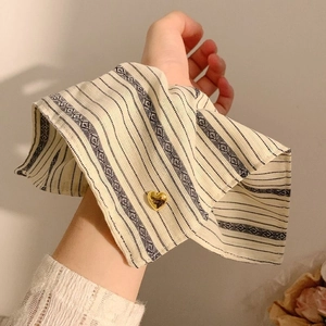 Detail of bohemian style beige wrist cuffs with striped pattern and gold heart button