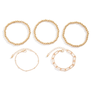 Five-piece gold beaded and chain bracelet set featuring a heart pendant on white background