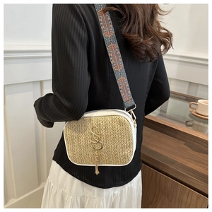 Detail of woven straw handbag with white leather trim and ethnic patterned wide strap