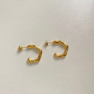 Detail view of gold wave C-shaped earrings with two sparkling small crystals