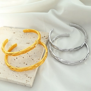 Irregular hammered gold and silver cuffs on stone and fabric background