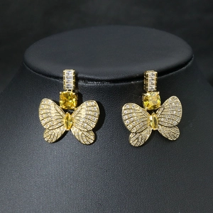 Elegant gold butterfly earrings with yellow gems and pavé zircon on a black stand