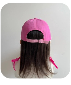 Detail of pink baseball cap back showing adjustable metal buckle on long hair model